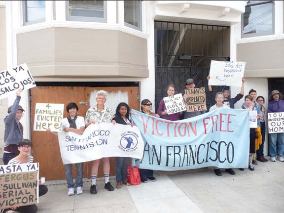 Protesters stand outside an open house where units cleared by Ellis Act evictions are for sale