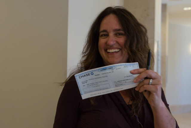 Tenant Carien McKay holds a check for the down payment that will take a Folsom Street building forever out of the private market