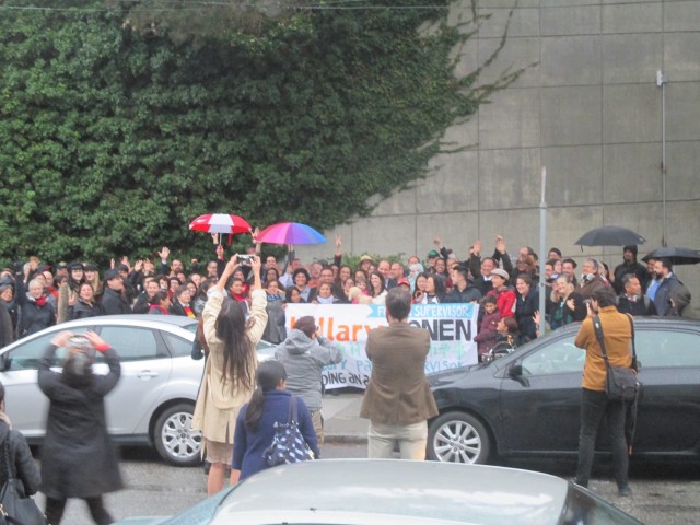 Large crowd fills the sidewalk in the rain