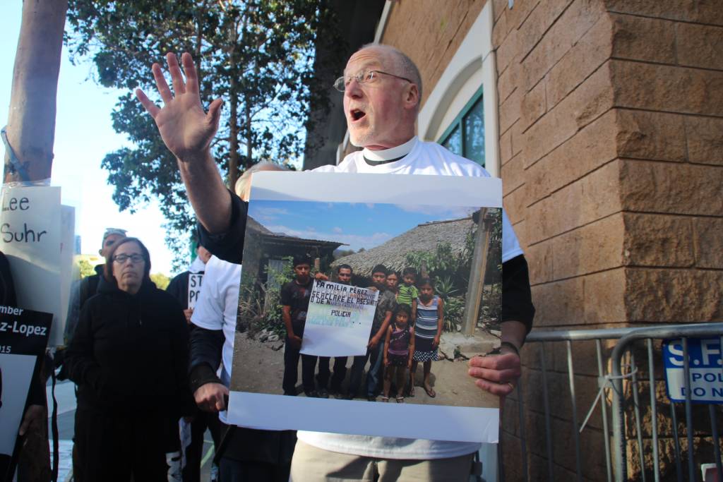 Father Richard Smith holds a photograph of Amilcar Perez Lopez's family in Guatemala, as he speaks to supporters gathered for silent vigil. Photo By - Sana Saleem