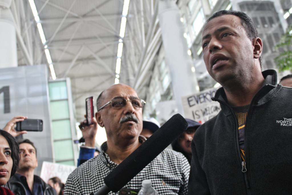 Mustafa Abuzeid, a Yemeni- America, stands alongside his father as he reunites with his family after being detained for 6 hours. Abuzeid has been a green card holder for the past 20 years and was returning home from Kaula Lumpur. Photo by Sana Saleem. 