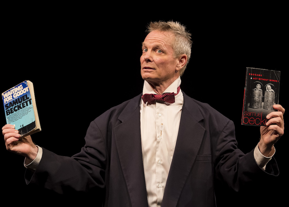 A photo of Bill Irwin holding up paperback versions of Beckett plays 'Waiting for Godot' and 'Endgame.'